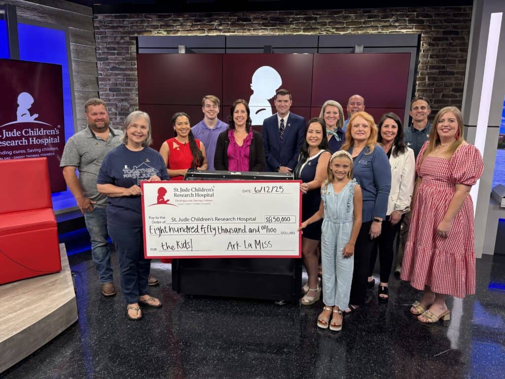 A group in Monroe stands indoors holding a Giveaway check for $850,000 made out to St. Jude Children's Research Hospital’s Dream Home.